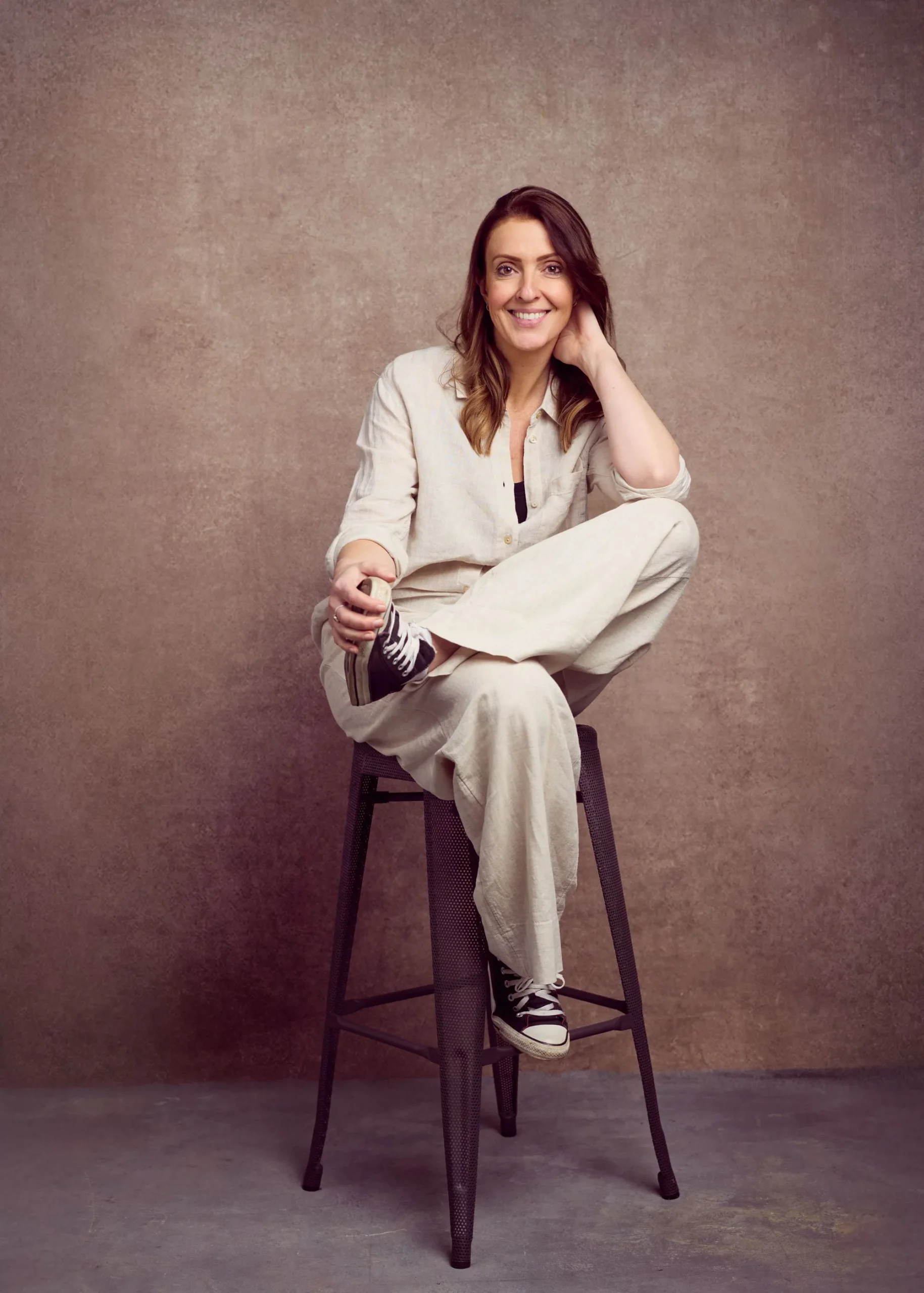 Steph Parry seated and smiling, photographed in a warm and welcoming portrait.